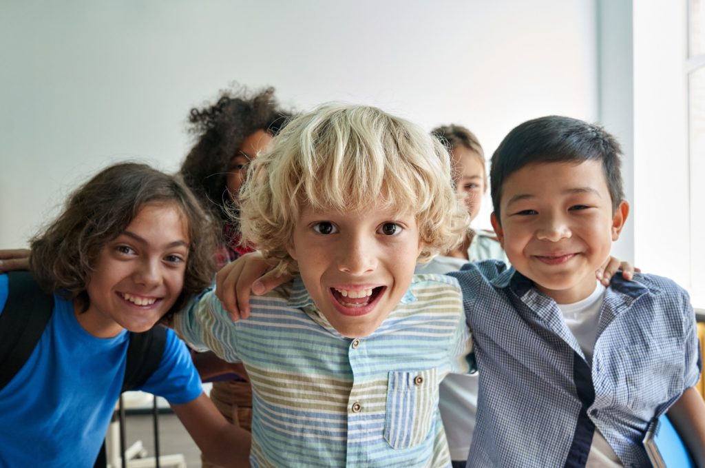 Portrait of happy cheerful smiling diverse kids having fun in classroom.