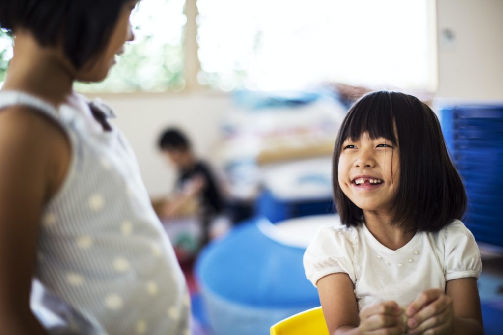 Two smiling girls in a classroom in a Japanese preschool.